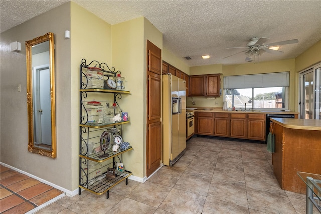 kitchen with ceiling fan, stainless steel range oven, fridge with ice dispenser, and a textured ceiling