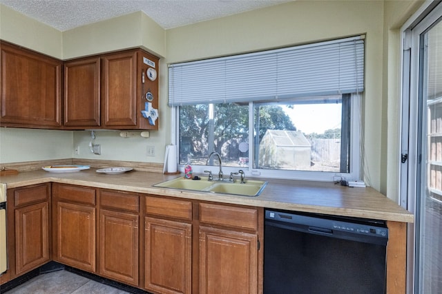 kitchen with black dishwasher, sink, and a textured ceiling