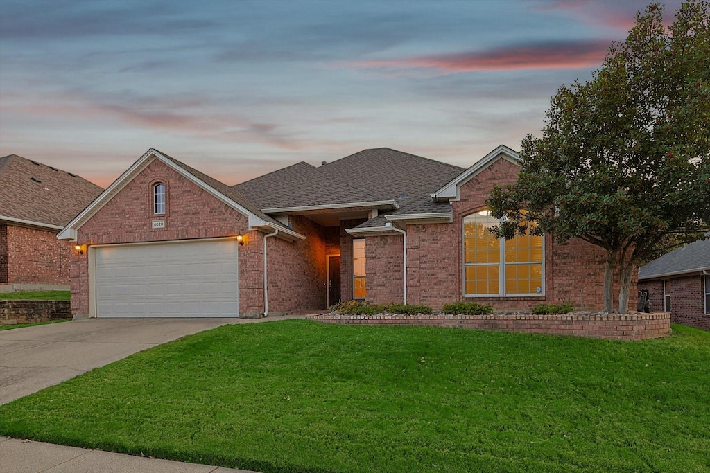 single story home featuring a garage and a yard