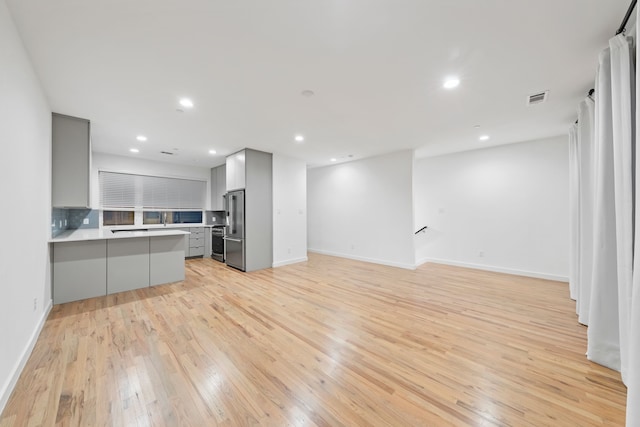 unfurnished living room with light wood finished floors, visible vents, recessed lighting, and baseboards