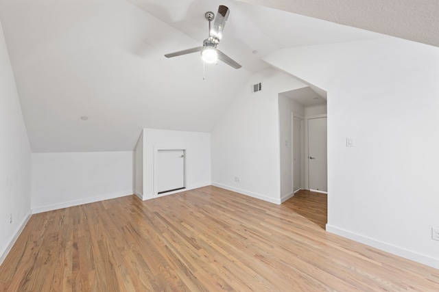 additional living space featuring visible vents, baseboards, light wood-style flooring, and vaulted ceiling