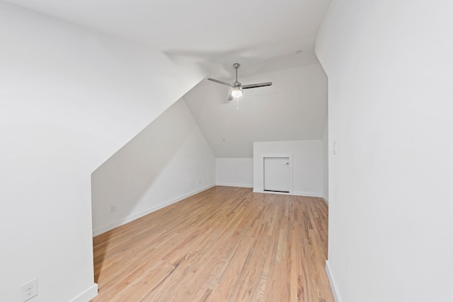 additional living space featuring light wood finished floors, baseboards, ceiling fan, and vaulted ceiling