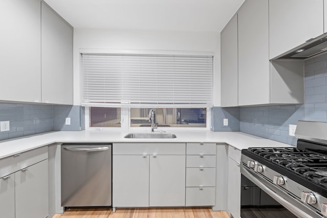 kitchen featuring a sink, light countertops, decorative backsplash, and stainless steel appliances