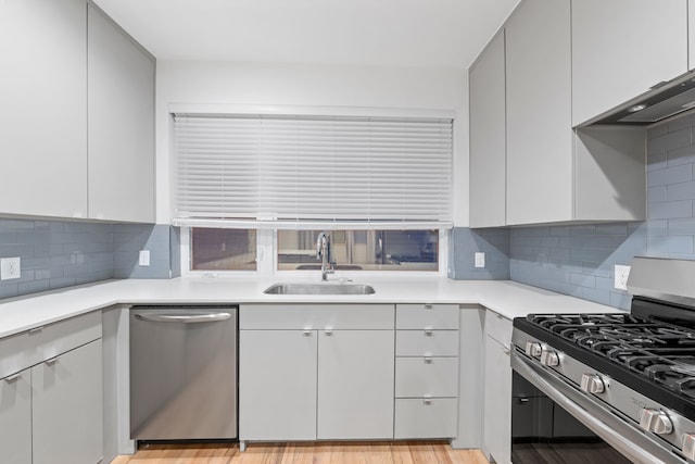 kitchen featuring backsplash, stainless steel appliances, light hardwood / wood-style flooring, and sink