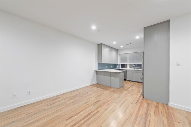 kitchen with light wood-type flooring, light countertops, recessed lighting, gray cabinets, and a peninsula