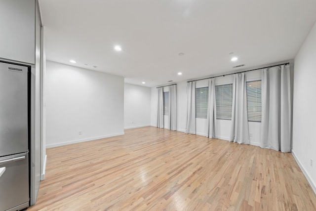 empty room featuring light wood finished floors, visible vents, recessed lighting, and baseboards