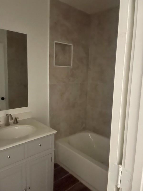 bathroom featuring hardwood / wood-style flooring, vanity, and tiled shower / bath