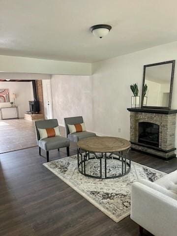 living room featuring a stone fireplace and dark hardwood / wood-style flooring