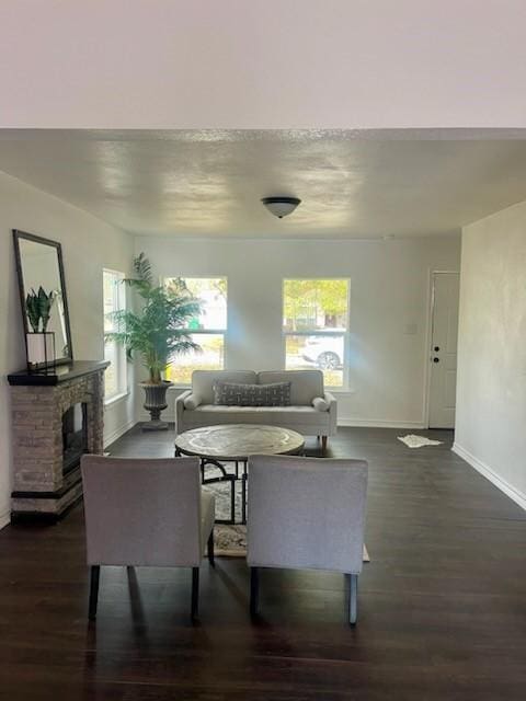 living room featuring dark wood-type flooring, plenty of natural light, and a fireplace