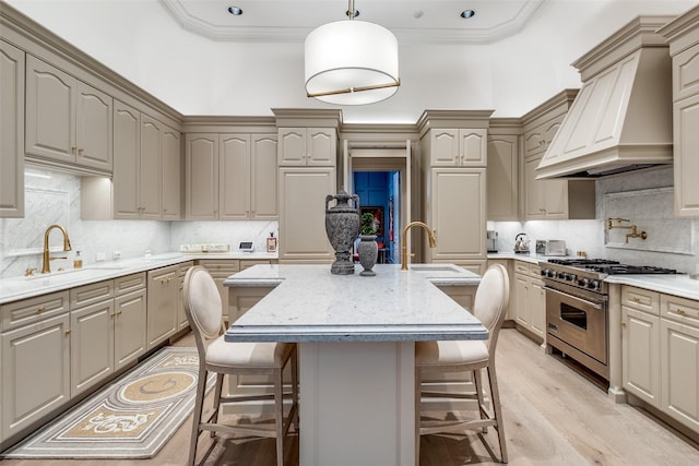 kitchen with sink, high end range, an island with sink, and custom range hood