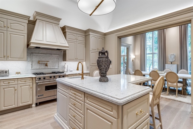 kitchen with sink, luxury stove, custom range hood, and light hardwood / wood-style flooring