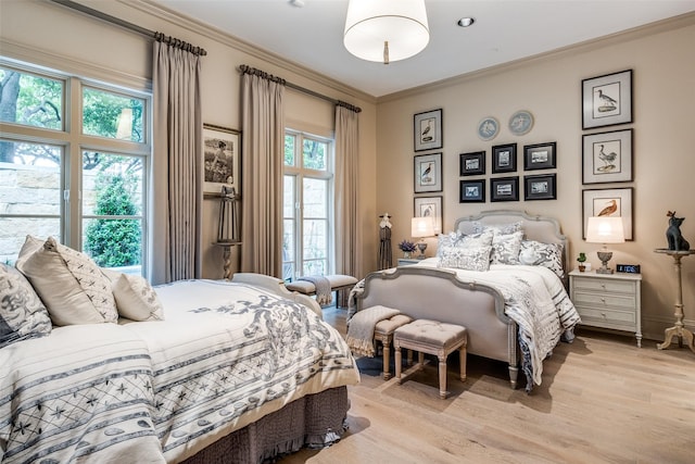 bedroom featuring multiple windows, light hardwood / wood-style floors, and ornamental molding