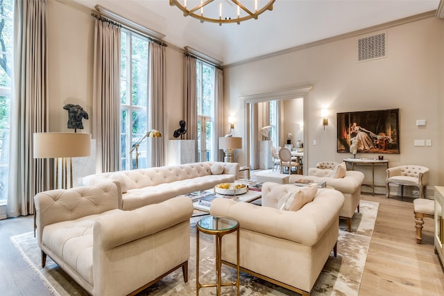 living room featuring light hardwood / wood-style floors, an inviting chandelier, and ornamental molding