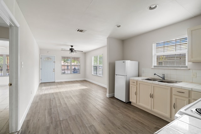 kitchen featuring ceiling fan, sink, wood-type flooring, white refrigerator, and tile counters