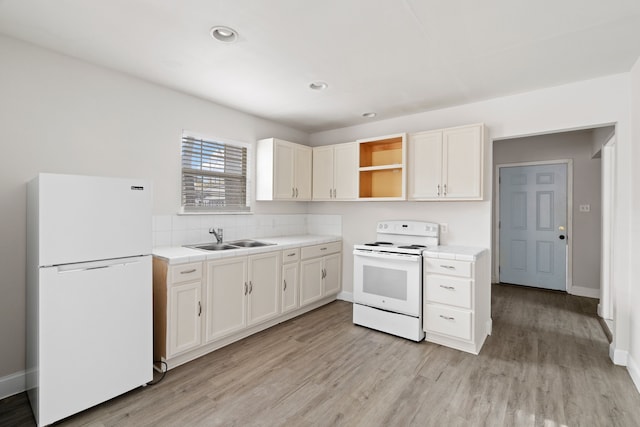 kitchen with white appliances, sink, decorative backsplash, light hardwood / wood-style floors, and white cabinetry