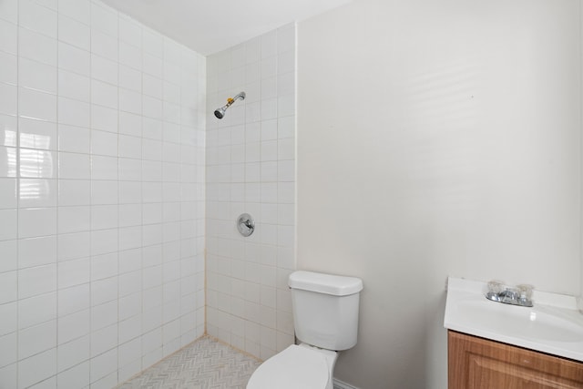 bathroom featuring a tile shower, vanity, and toilet