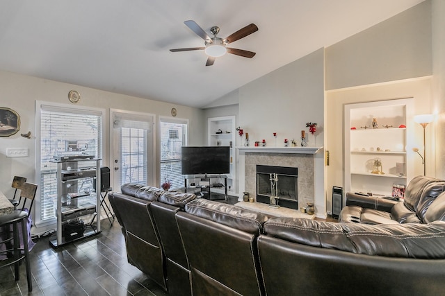 living room with built in shelves, ceiling fan, dark hardwood / wood-style floors, lofted ceiling, and a tiled fireplace