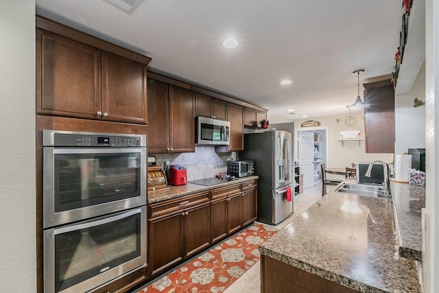 kitchen featuring dark brown cabinetry, stainless steel appliances, hanging light fixtures, and sink