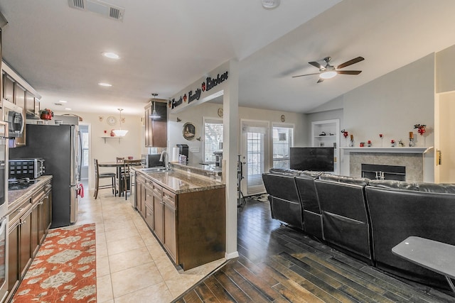 kitchen with dark stone counters, sink, vaulted ceiling, light hardwood / wood-style flooring, and ceiling fan