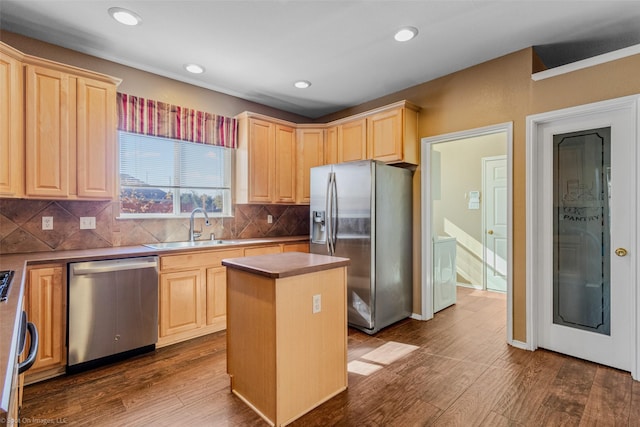 kitchen featuring appliances with stainless steel finishes, sink, light brown cabinets, wood-type flooring, and a center island