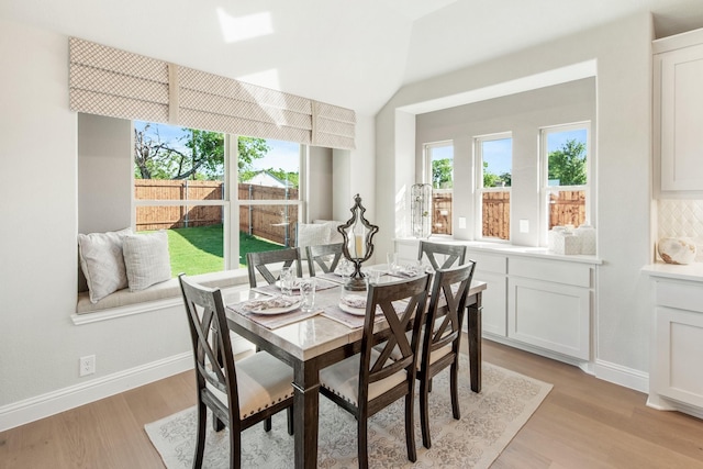 dining room with vaulted ceiling and light wood-type flooring