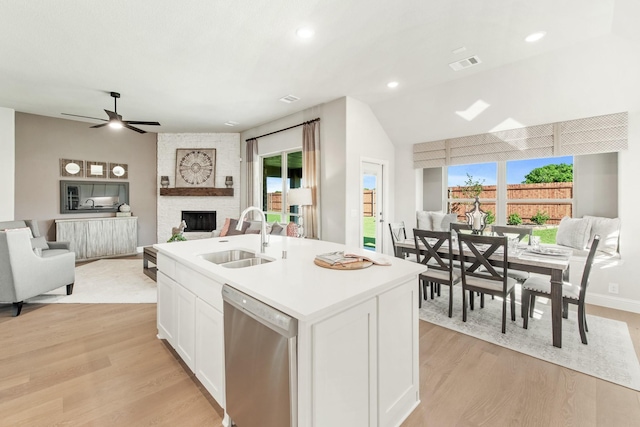 kitchen featuring sink, white cabinetry, dishwasher, an island with sink, and a fireplace