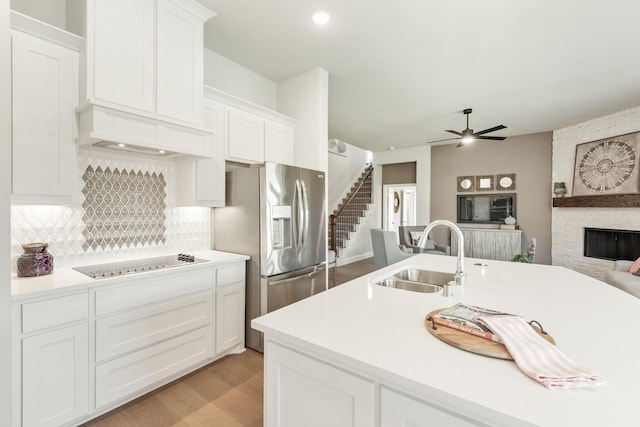 kitchen featuring white cabinetry, sink, stainless steel fridge, and black electric cooktop