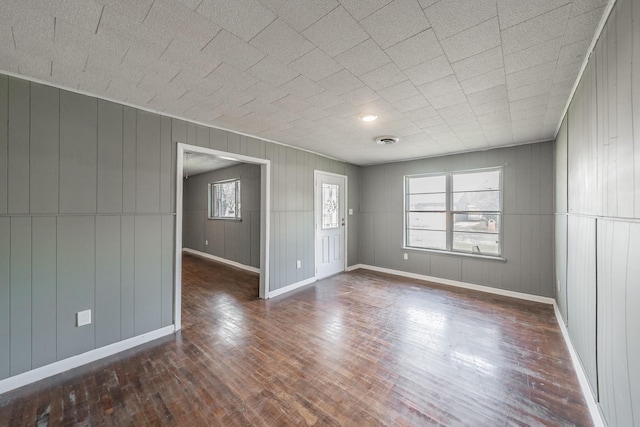 spare room featuring wood walls, dark hardwood / wood-style flooring, and plenty of natural light