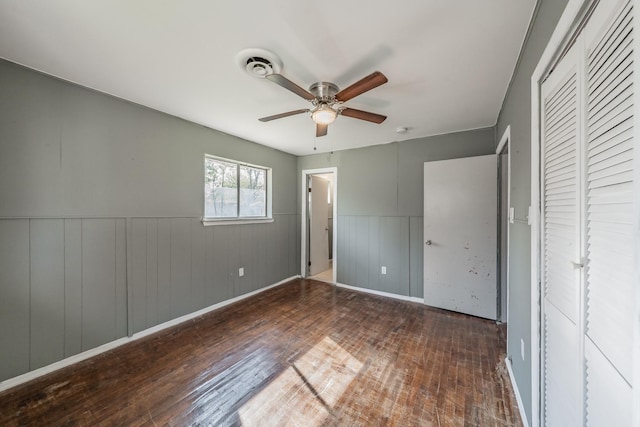 unfurnished bedroom with a closet, dark hardwood / wood-style floors, and ceiling fan