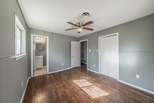 unfurnished bedroom with dark wood-type flooring, sink, ensuite bath, ceiling fan, and a closet