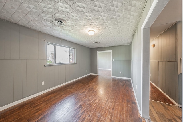 spare room with wooden walls and dark wood-type flooring