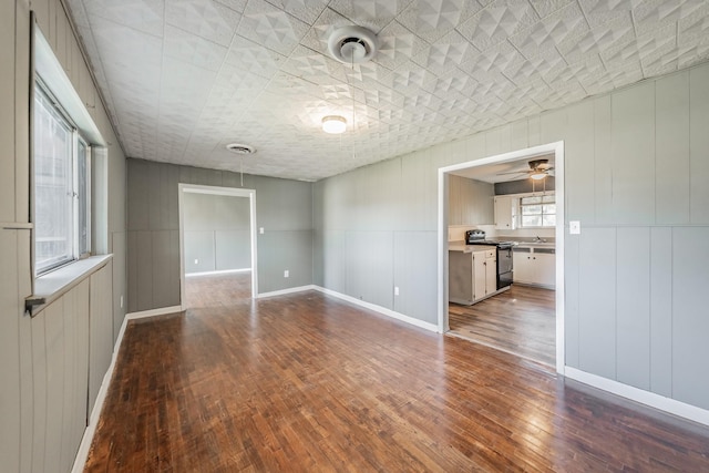 unfurnished room with hardwood / wood-style flooring, ceiling fan, sink, and a wealth of natural light