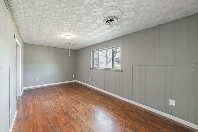 empty room with hardwood / wood-style floors and wood walls