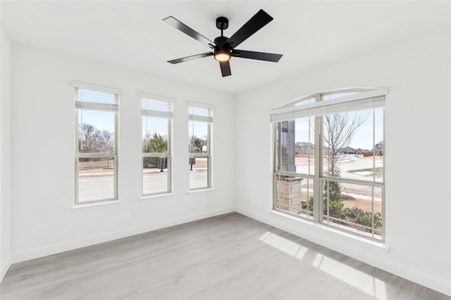 empty room featuring a ceiling fan, light wood-style floors, and baseboards