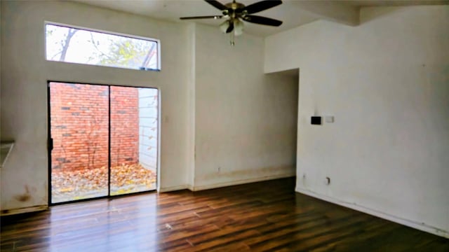 unfurnished room featuring ceiling fan, a towering ceiling, beamed ceiling, and dark wood-type flooring