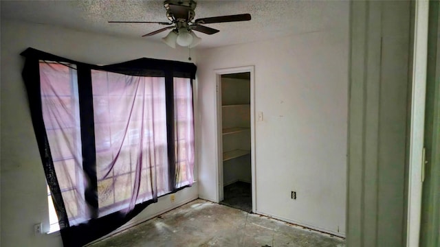 unfurnished bedroom with a spacious closet, ceiling fan, and a textured ceiling