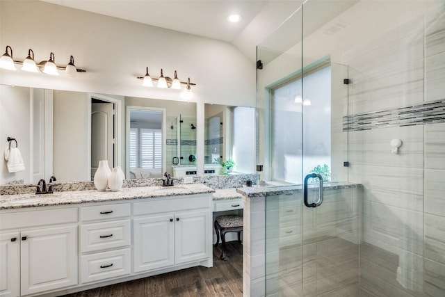 bathroom featuring vanity, hardwood / wood-style flooring, vaulted ceiling, and a shower with door