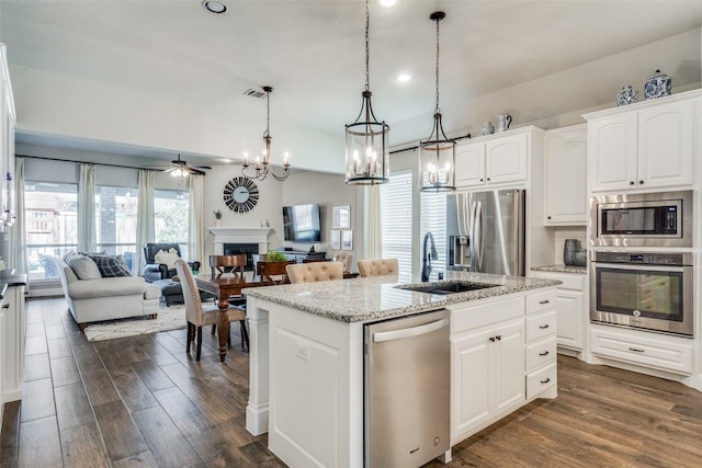 kitchen featuring a wealth of natural light, dark wood-type flooring, an island with sink, and stainless steel appliances