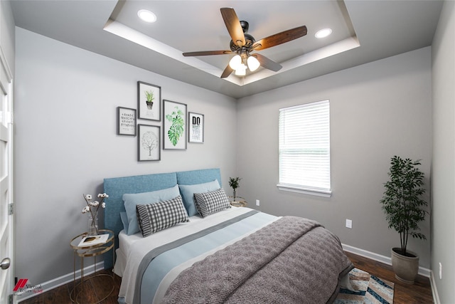 bedroom featuring dark hardwood / wood-style floors, a raised ceiling, and ceiling fan