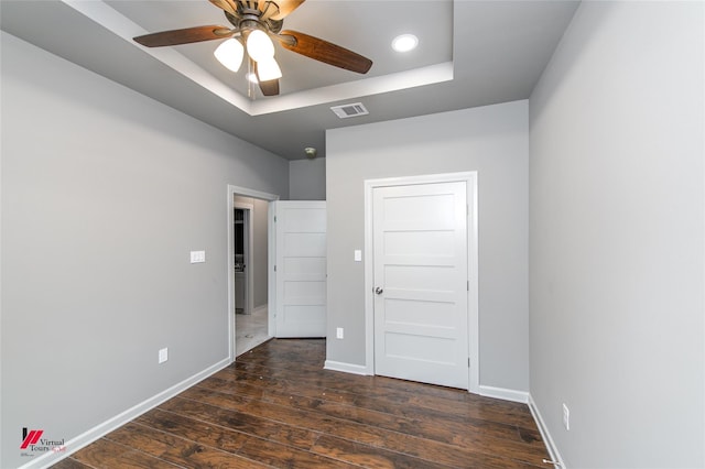 unfurnished bedroom with a raised ceiling, ceiling fan, and dark hardwood / wood-style flooring