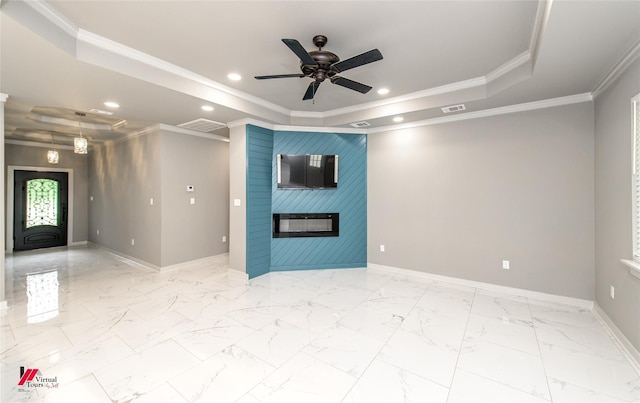 unfurnished living room featuring a tray ceiling, ceiling fan, a fireplace, and ornamental molding