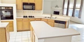 kitchen with kitchen peninsula, light brown cabinetry, sink, black appliances, and a kitchen island