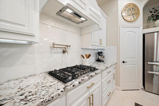 kitchen with appliances with stainless steel finishes, white cabinets, backsplash, and light stone countertops