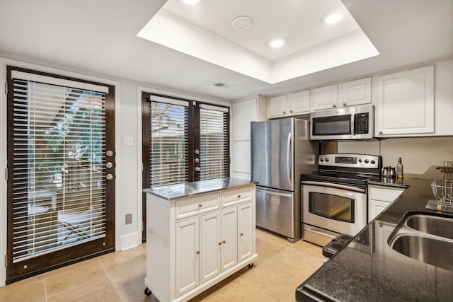 kitchen with a healthy amount of sunlight, a kitchen island, dark stone counters, and appliances with stainless steel finishes