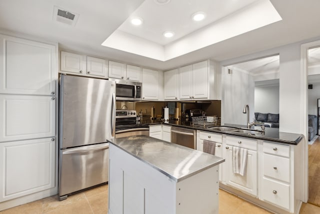 kitchen with appliances with stainless steel finishes, sink, light tile patterned floors, a center island, and white cabinetry