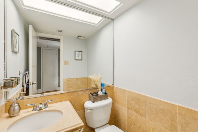 bathroom with vanity, tile walls, and toilet