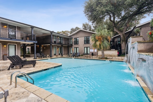 view of swimming pool with pool water feature and a patio