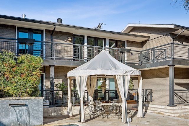 back of property featuring a gazebo, a patio, and a balcony