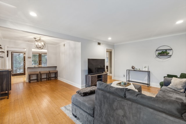 living room featuring hardwood / wood-style floors, a notable chandelier, and crown molding