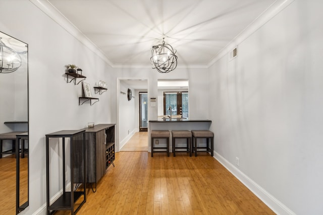 foyer with sink, french doors, an inviting chandelier, light hardwood / wood-style flooring, and ornamental molding